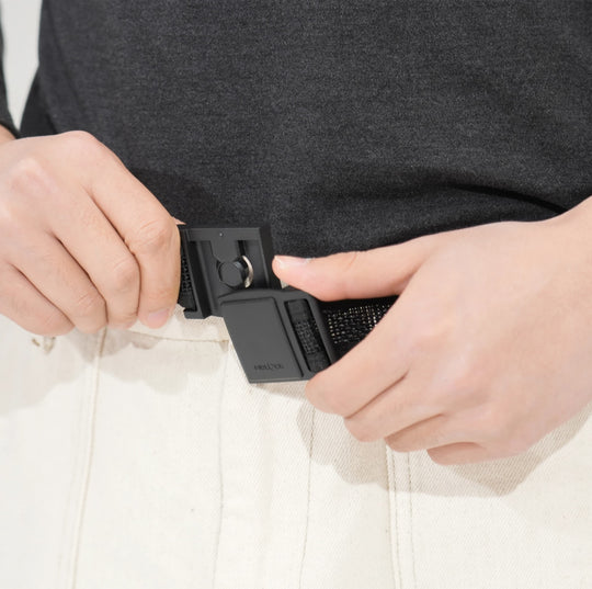 Hands adjusting FIDLOCK buckle on tactical belt with light pants