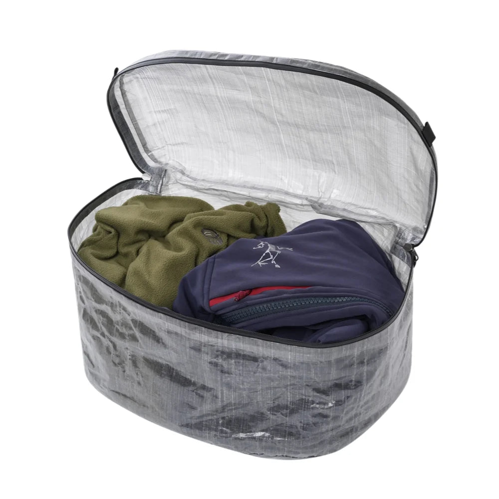Open packing cube with green and blue clothing items on a white background