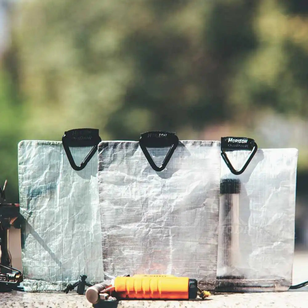 Three ultralight lantern shade packages with carabiners outdoors